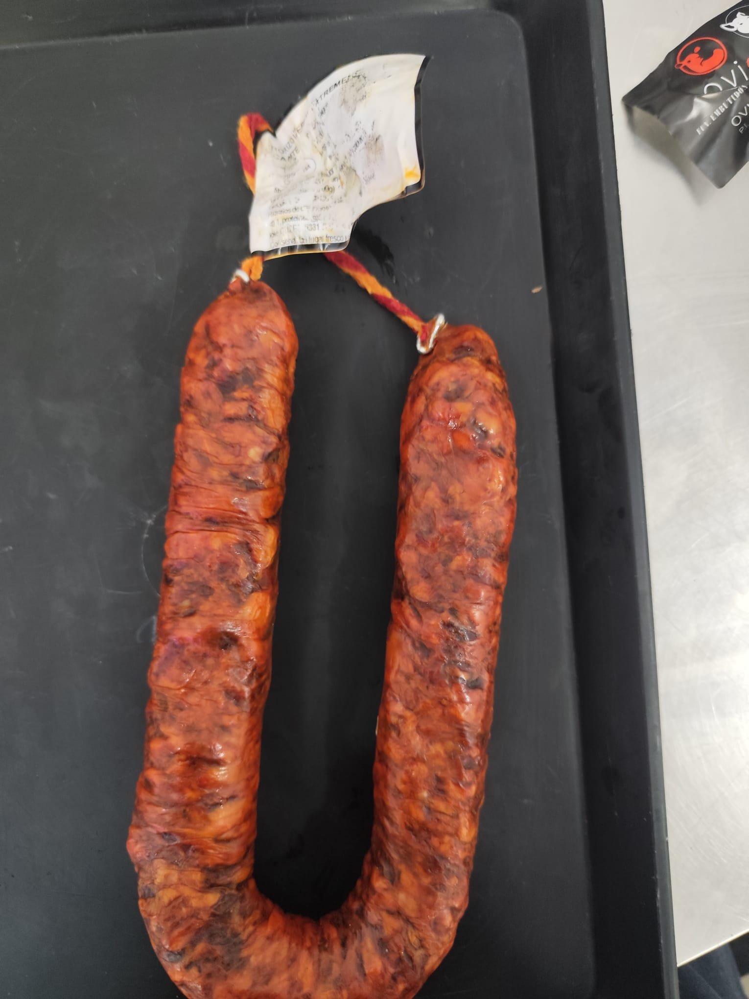 Chorizo picante extremeño en herradura, curado y atado con cordel rojo y amarillo