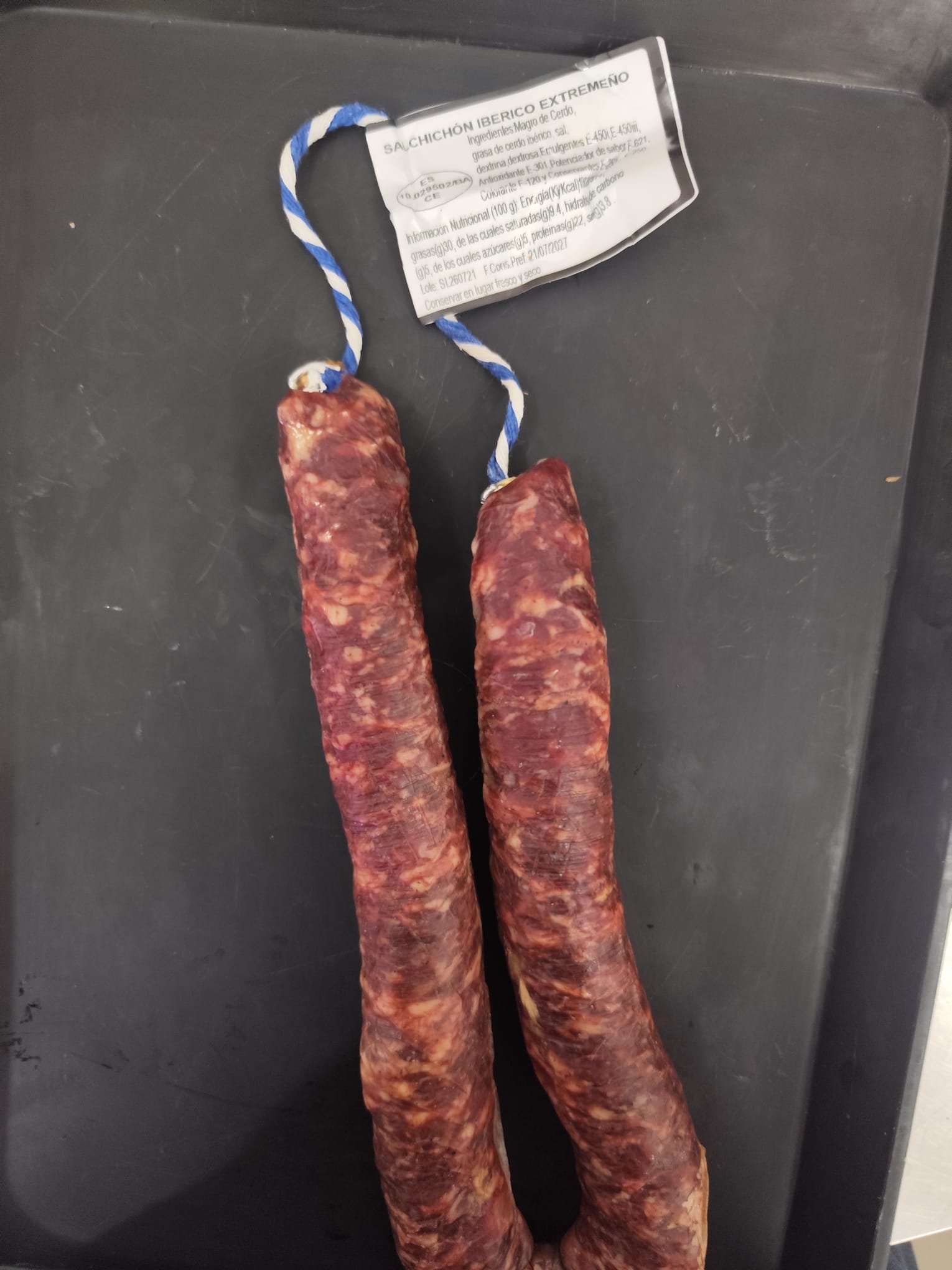 Dos salchichones ibéricos extremeños en herradura, curados y atados con cordel azul y blanco