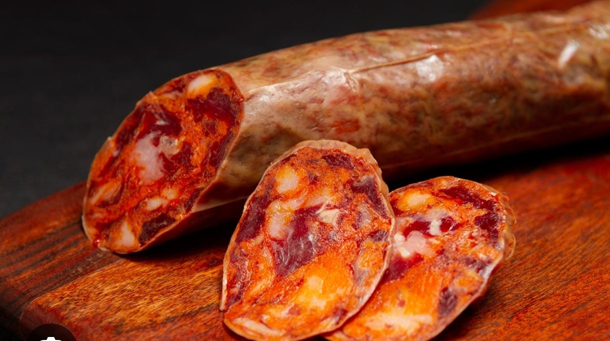 Chorizo curado con el corte a la vista y dos lonchas sobre una tabla de madera