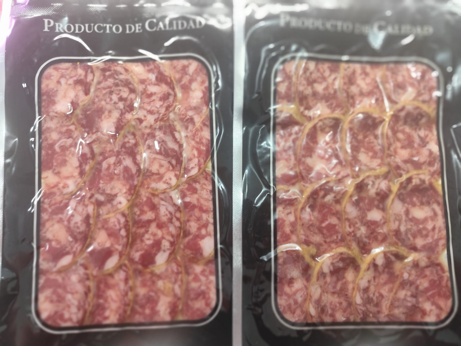 Dos envases al vacío de salchichón cular extremeño loncheado, con lonchas de magro rosado y tocino blanco